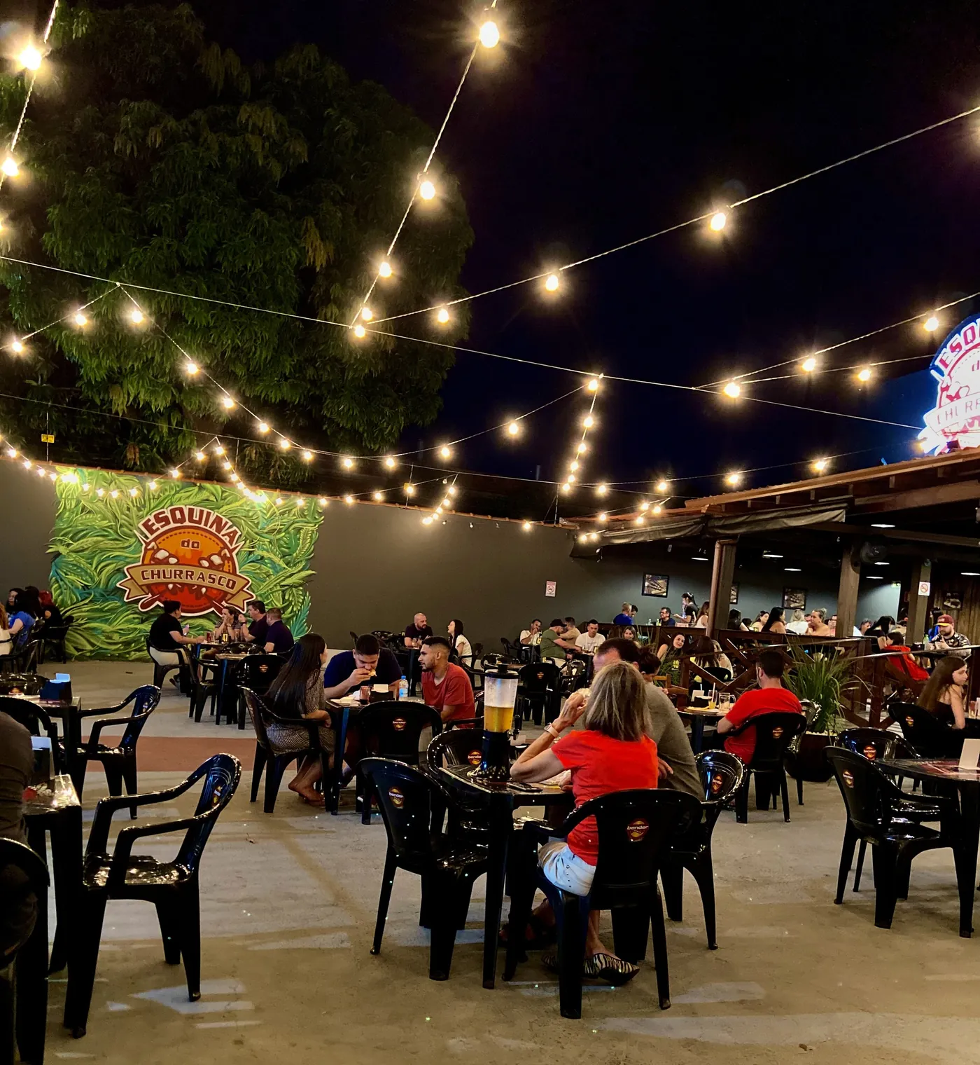 Ambiente externo da Esquina do Churrasco em Sapucaia do Sul com luzes e mesas cheias